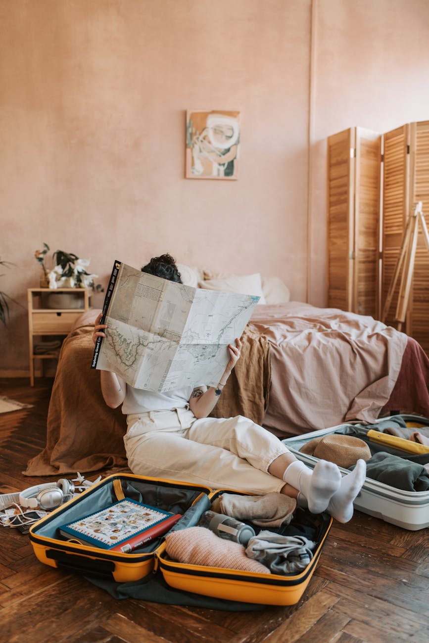 Woman mid-pack surrounded by travel bags and a map, planning her vacation stress-free